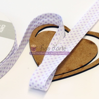 Fita branca com bolinhas lilás enrolada em rolo junto de placa em forma de coração