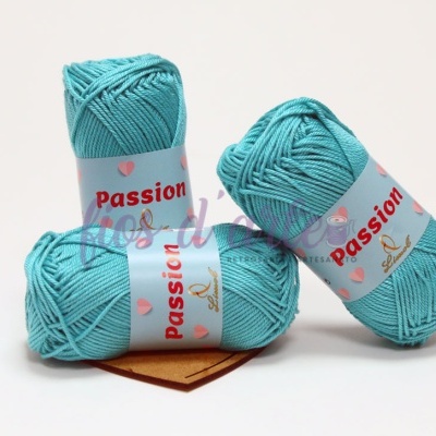 Três novelos de lã azul turquesa com rótulos brancos e vermelhos