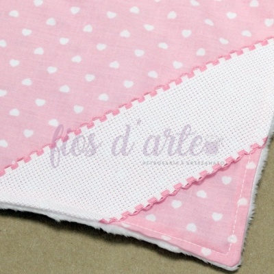 Pano rosa com corações brancos e bordado rosa numa superfície bege