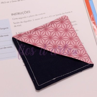 Pano de tecido rosa e azul escuro sobre livro de instruções de costura