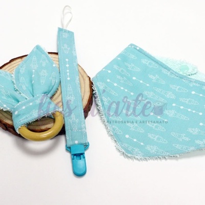 Conjunto para bebé com faixa de tecido, mordedor de madeira, fita para chupeta e babete, todos azuis com padrão de peixes brancos.