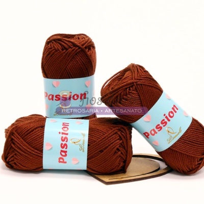 Três novelos de lã castanha com etiquetas azuis claras e texto vermelho Passion