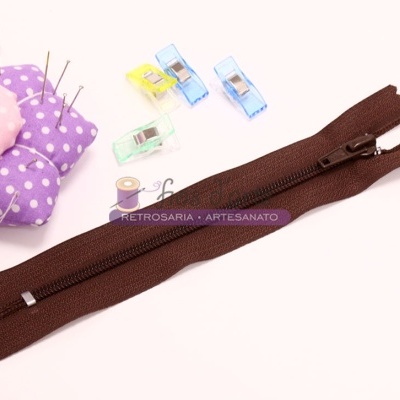 Zíper castanho com alfineteiro roxo, clipes coloridos e carretel de linha