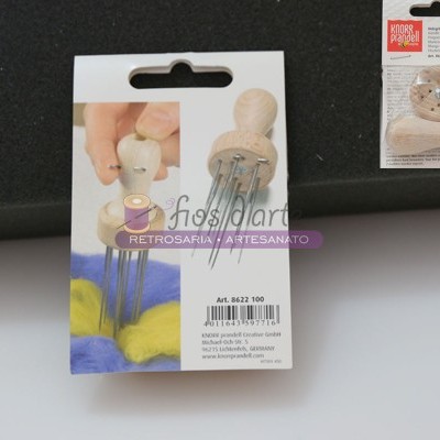 Agulhador de lã de madeira com vários alfinetes, em embalagem de papel com texto e código de barras.