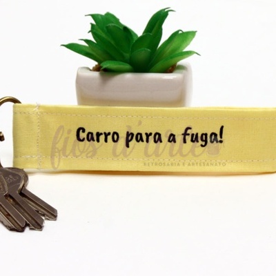 Chaveiro amarelo com texto e chaves ao lado de planta suculenta