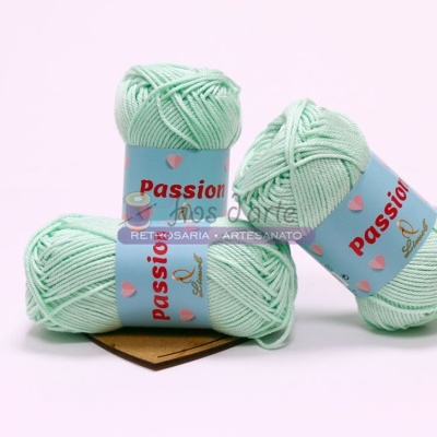 Três novelos de fio verde-menta com etiquetas azuis claras Passon na superfície branca