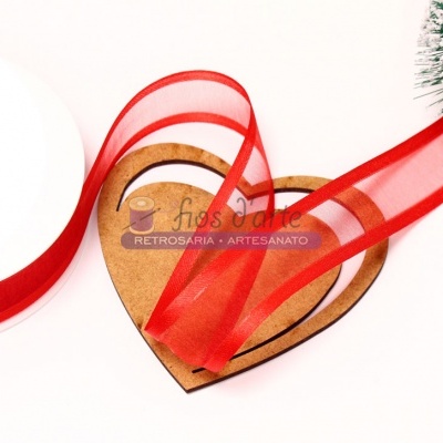 Fita vermelha translúcida em carretel sobre coração de cortiça e árvore de Natal artificial