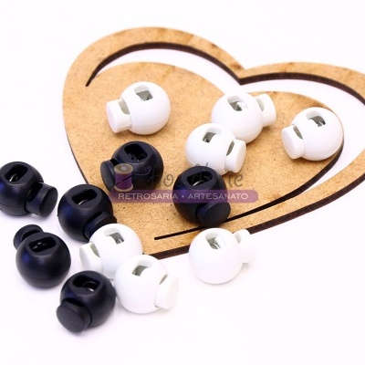 Bloqueadores de cortina em plástico preto e branco sobre forma de coração em madeira
