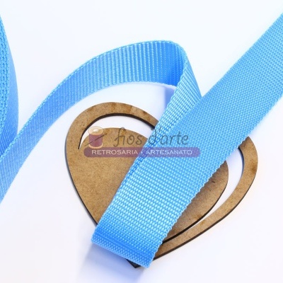 Fita azul clara sobre base de cartão em forma de coração com etiqueta numa superfície branca