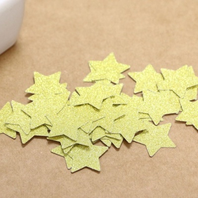 Estrelas douradas de papel glitter sobre superfície castanha