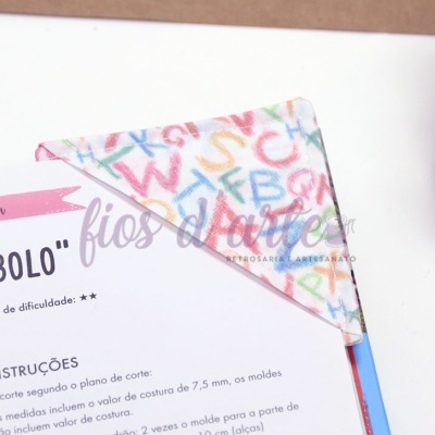 Guardanapo de pano com padrão colorido de letras maiúsculas sobre folha de instruções