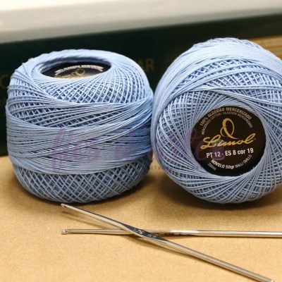 Dois novelos de linha azul clara da marca Lindal com agulhas de croché prateadas