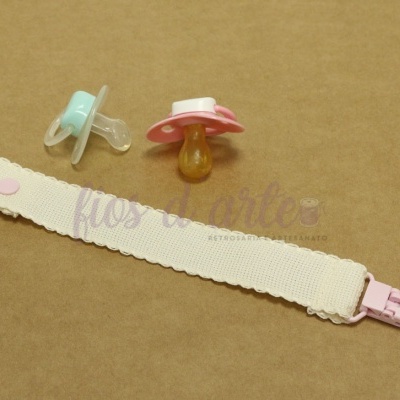 Dois chupetas em silicone e plástico com fita de tecido branca e botão e clipe rosa