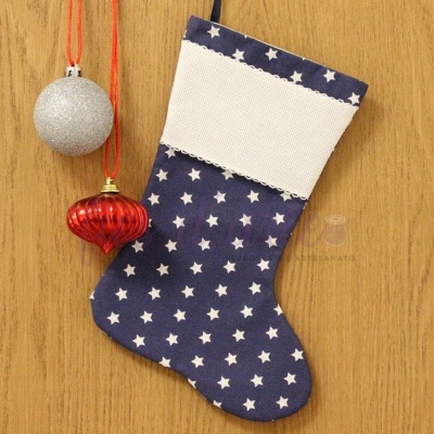 Meia de Natal azul com estrelas brancas e punho branco pendurada em madeira com duas decorações vermelha e prateada