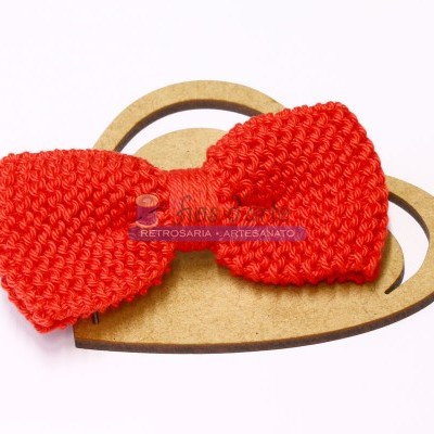 Laço vermelho trançado sobre coração de madeira