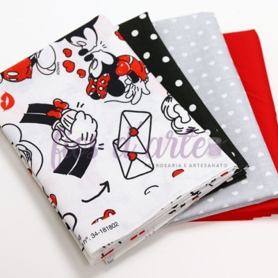 Quatro tecidos dobrados com padrões variados, incluindo desenhos animados, bolinhas, corações e cor sólida.