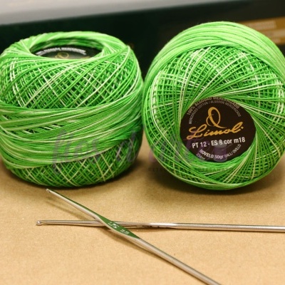 Dois novelos de linha verde com agulhas de metal em fundo neutro