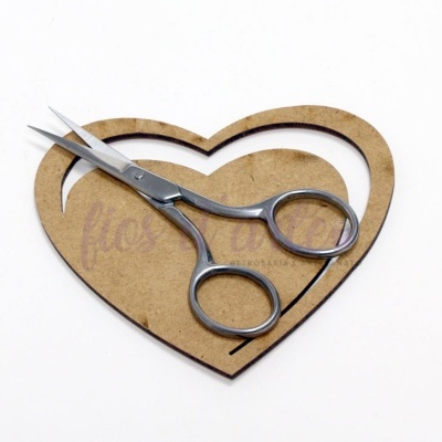Tesoura pequena de aço sobre base cartão em forma de coração