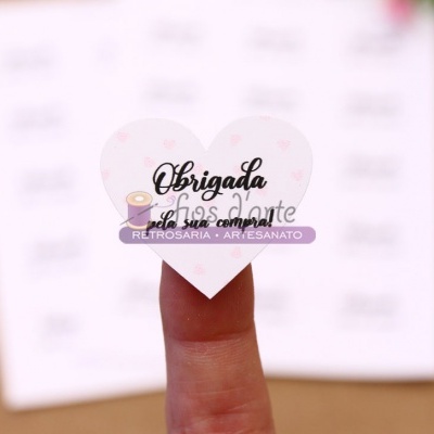 Etiqueta em forma de coração com texto de agradecimento colocada na ponta do dedo