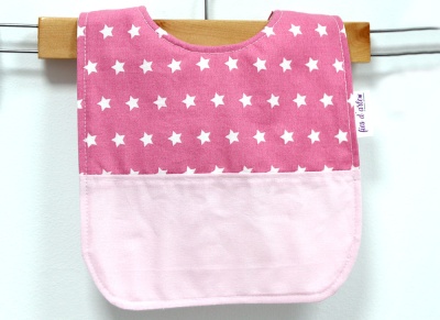 Babete rosa com estrelas brancas pendurado na madeira