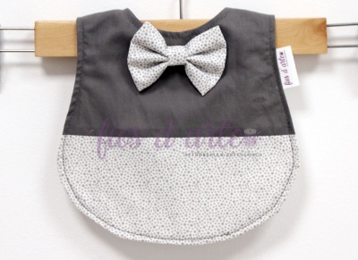 Babete para bebé cinzento e branco com laço pendurado numa cabide de madeira