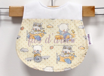 Babete de bebé creme e branco com padrão de ursos em aviões.