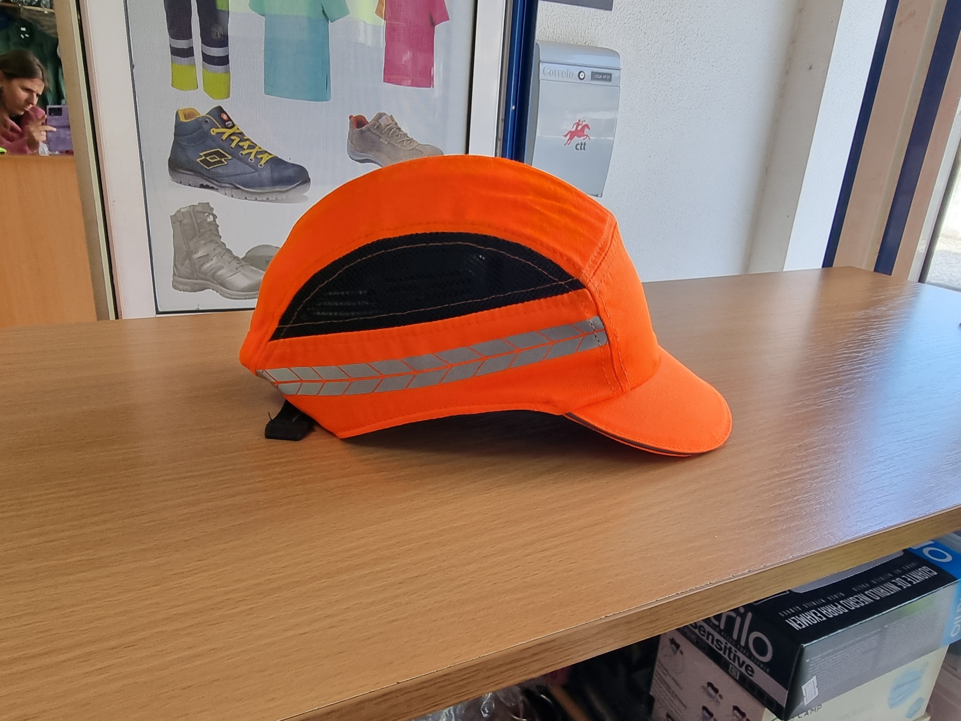 Boné laranja com faixa refletora cinza em mesa de madeira