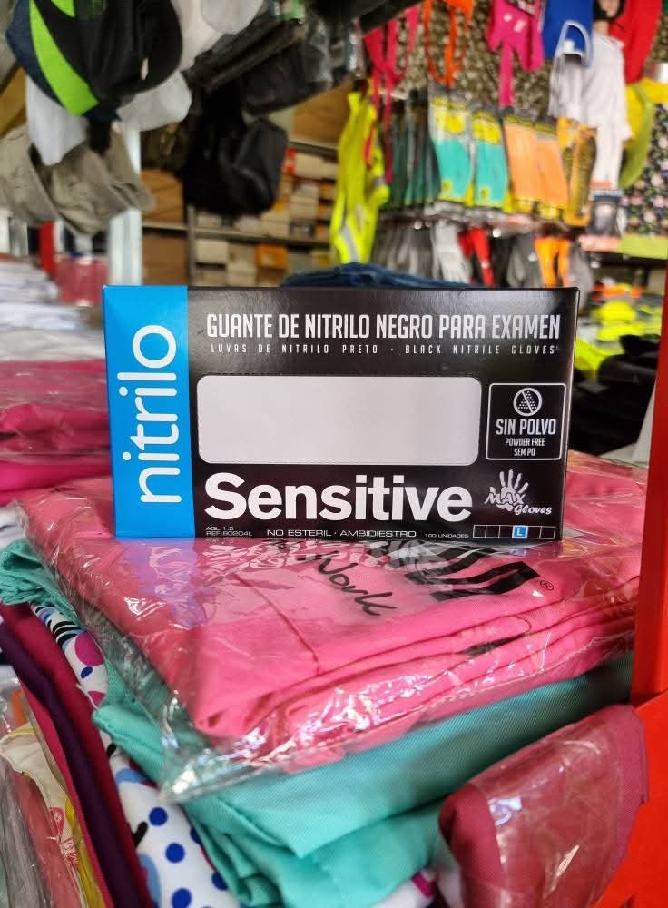Caixa de luvas de nitrilo preto Sensitive em cima de roupas coloridas embaladas.