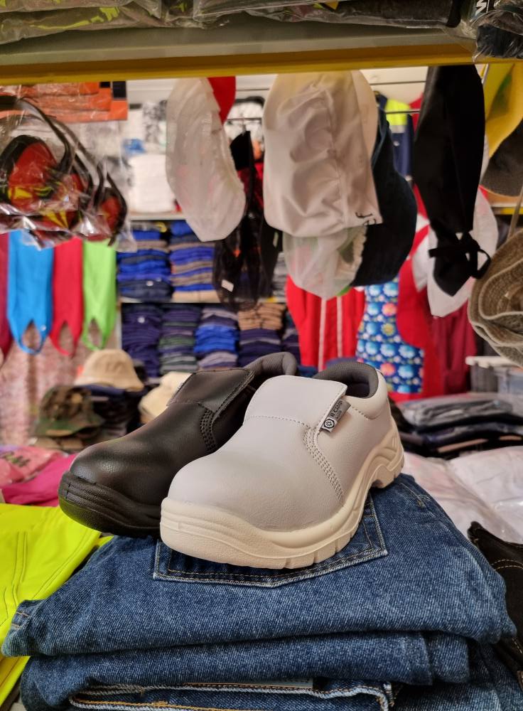 Sapatos de trabalho couro preto e branco sobre calças de ganga em loja de roupa