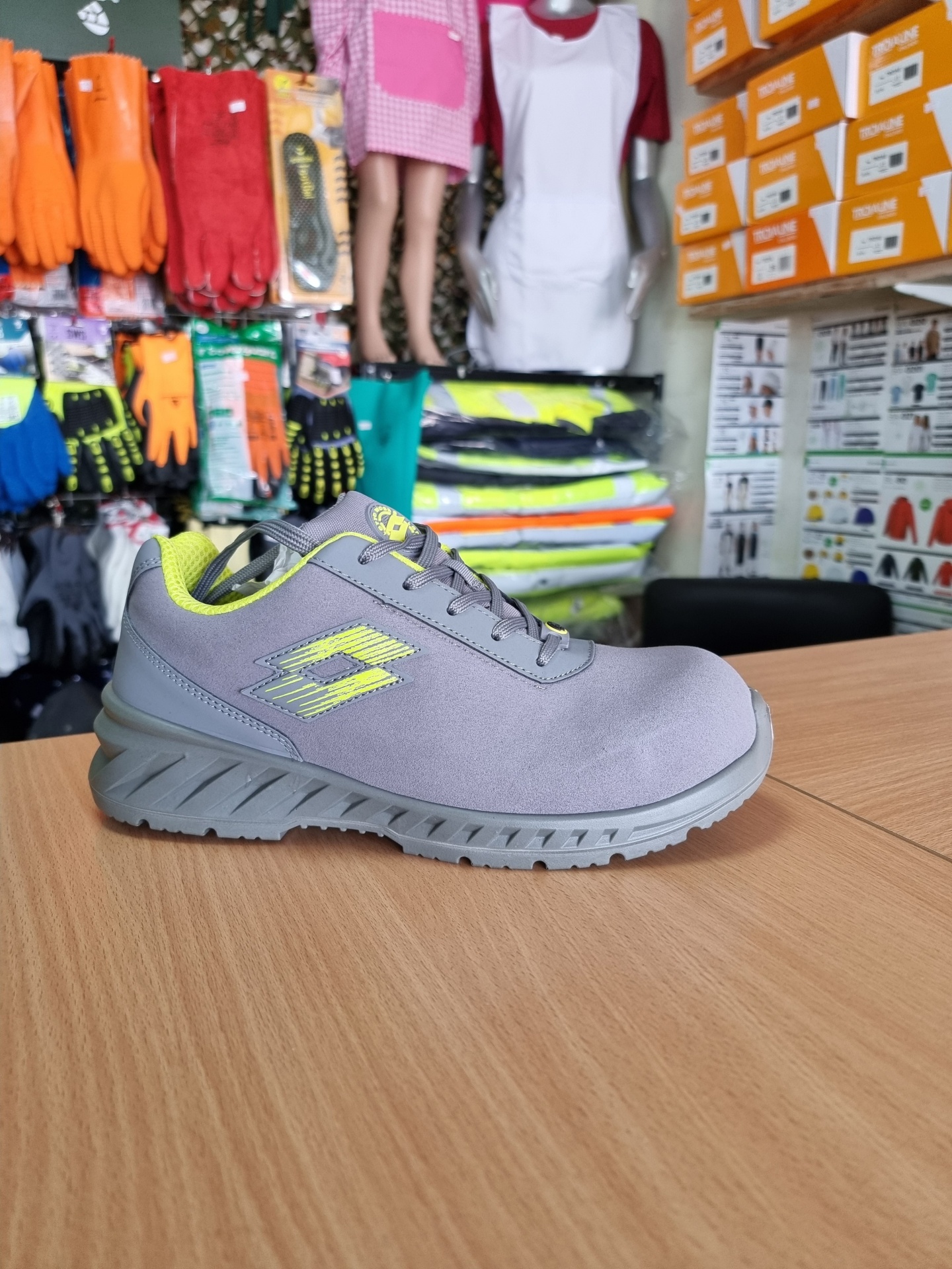 Tênis desportivo cinzento com detalhes amarelo fluorescente numa mesa de madeira