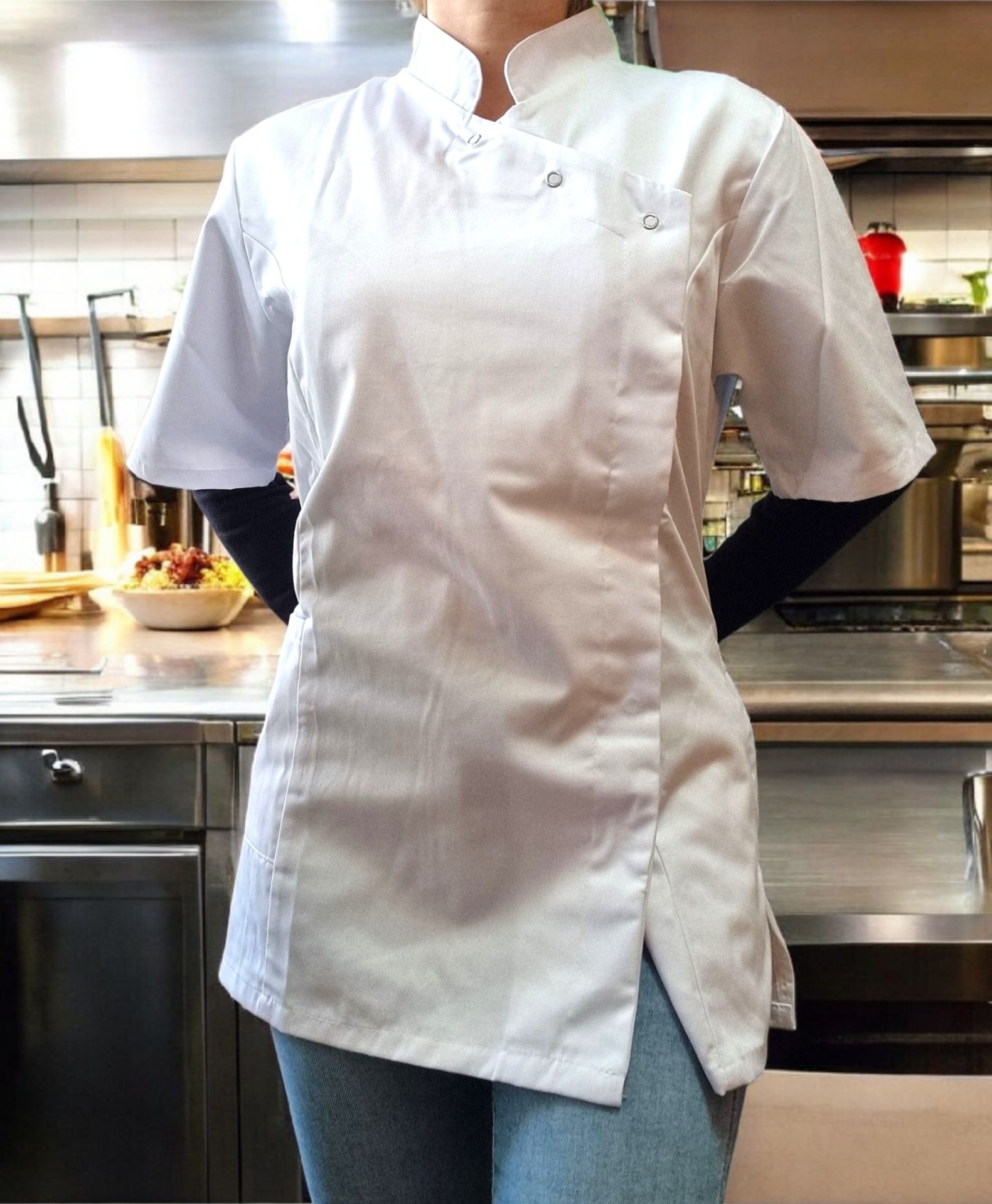 Bata de chef branca de manga curta com fecho cruzado e botões metálicos numa cozinha profissional