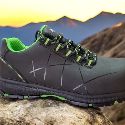 Sapato desportivo preto com detalhes verdes sobre pedra ao ar livre