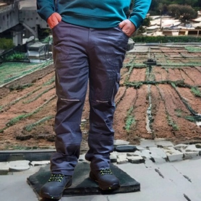 Calças de trabalho cinza com bolsos laterais e botas pretas com atacadores verdes em ambiente urbano