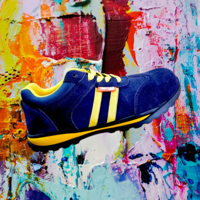 Ténis desportivo azul e amarelo sobre fundo de pintura colorida