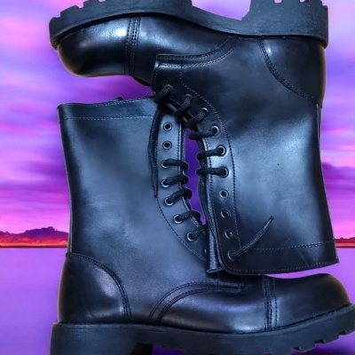 Bota preta de couro com cadarço, sola grossa, contra fundo roxo-rosa