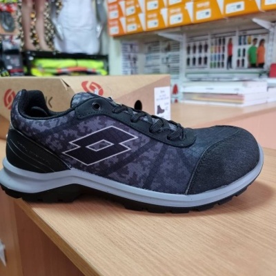 Ténis preto e cinzento com símbolo losango e sola branca sobre mesa de madeira