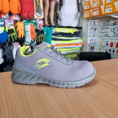 Tênis desportivo cinzento com detalhes amarelo fluorescente numa mesa de madeira