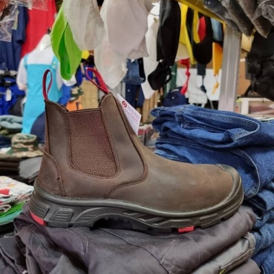 Botim de couro castanho numa pilha de roupas em loja