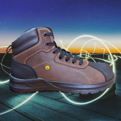 Bota de trabalho castanha com bico reforçado preto e atacadores pretos sobre madeira ao pôr do sol
