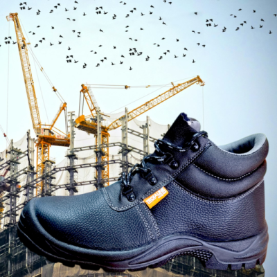Bota de trabalho preta em pele texturada com etiqueta PROMANI e fundo de construção.