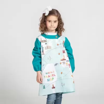 Criança com bata azul claro com ilustração de mapa do mundo e botões laranja