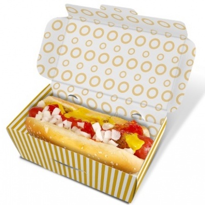 Hot dog num pão com sementes de sésamo numa caixa de papel com padrão de círculos e riscas douradas.