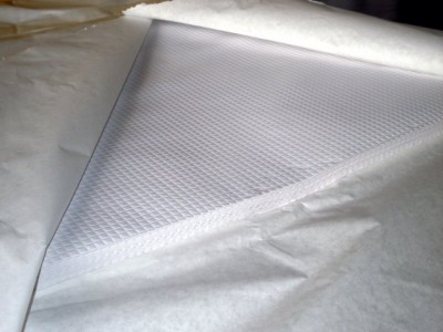 tecido branco com padrão quadriculado desenrolado sobre pano branco