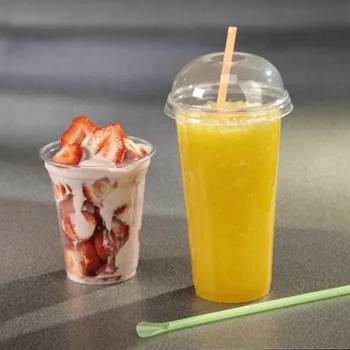 Copo transparente com creme e morangos e copo plástico com bebida amarela e canudo.