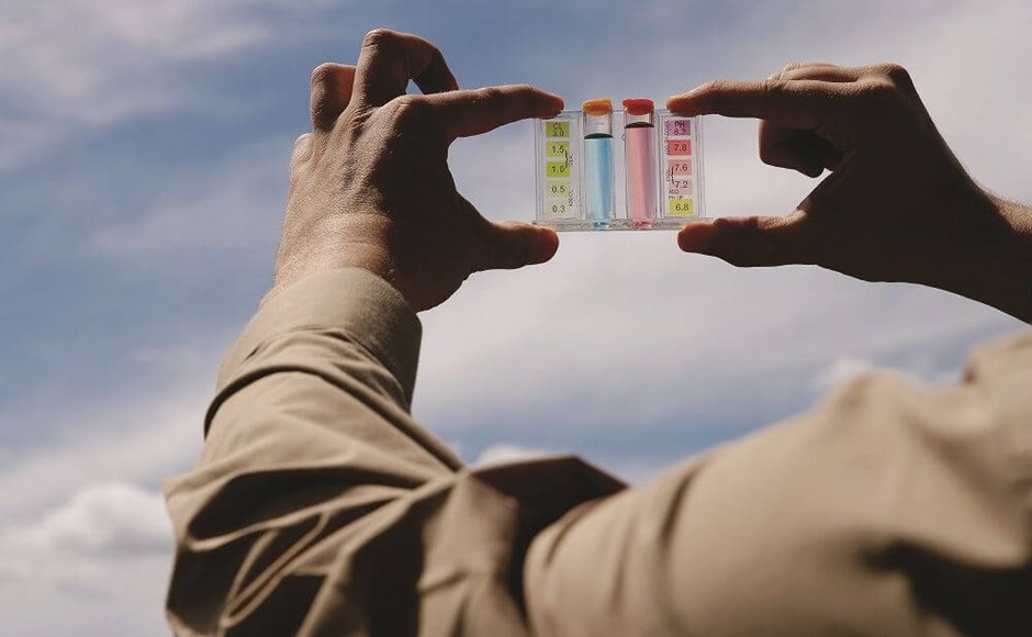Mãos segurando placa transparente com tubos coloridos contra o céu