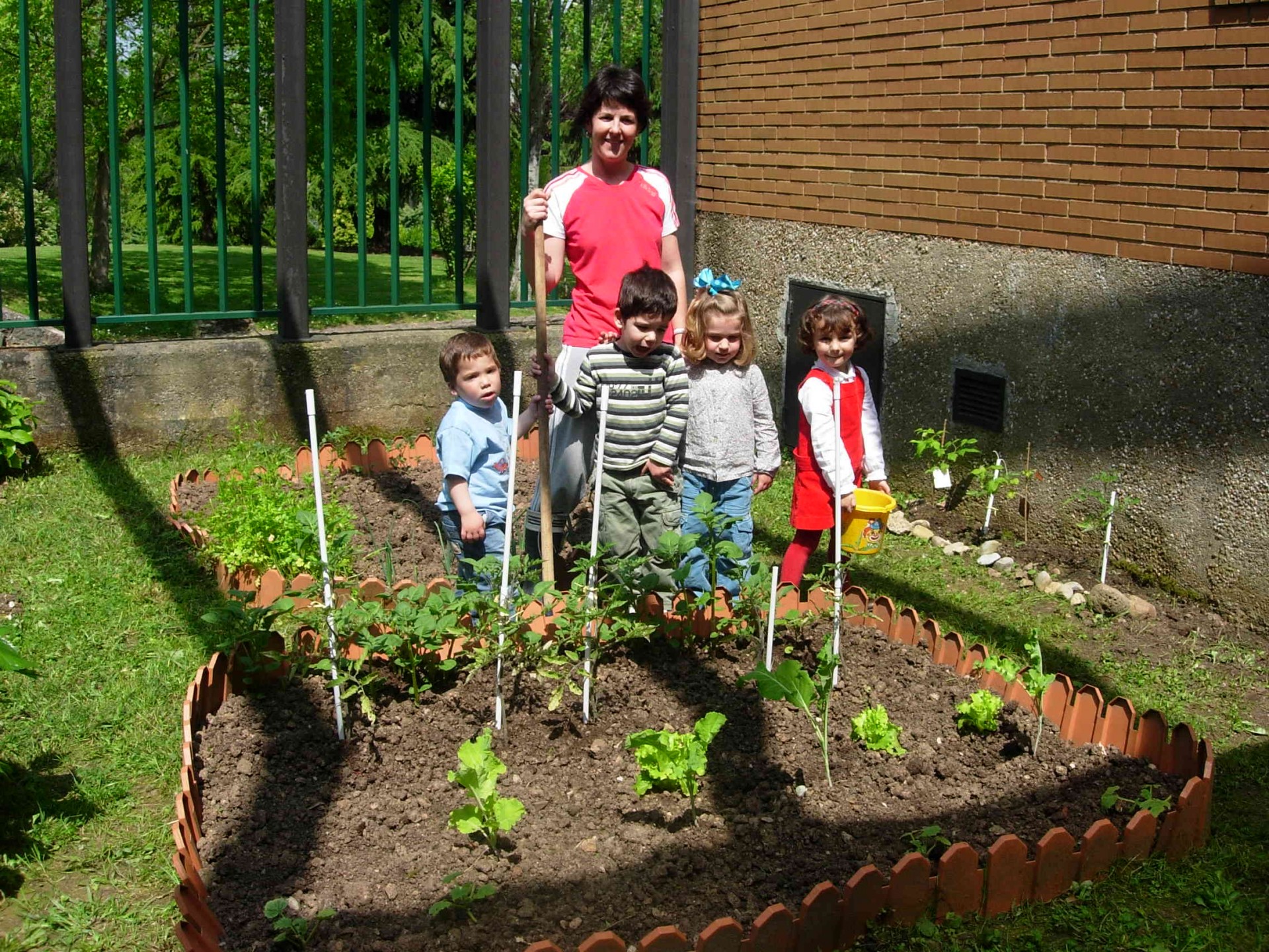 Horta exterior com canteiro de madeira e pessoas ao lado