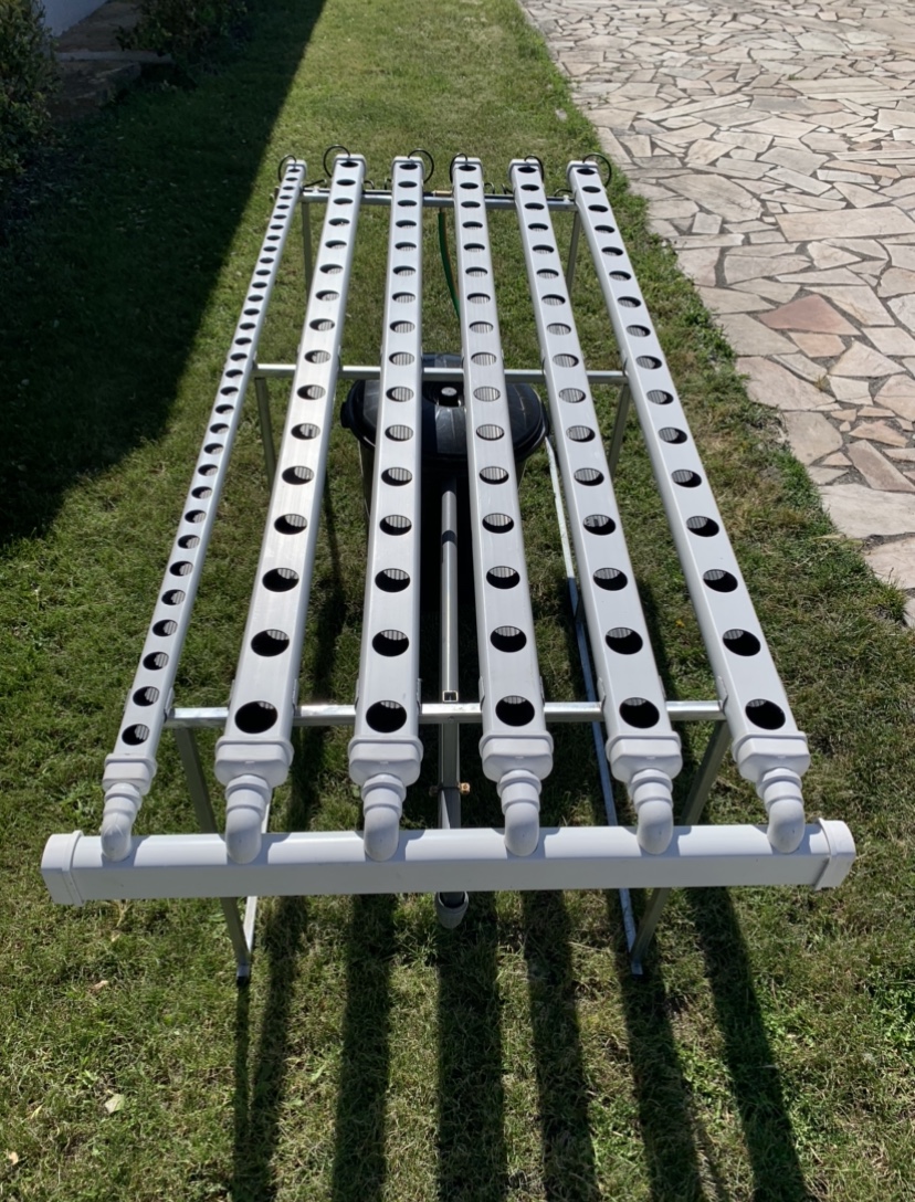 Hydro 110 Horizontal Sistema hidropônico com tubos brancos perfurados sobre suporte metálico na relva