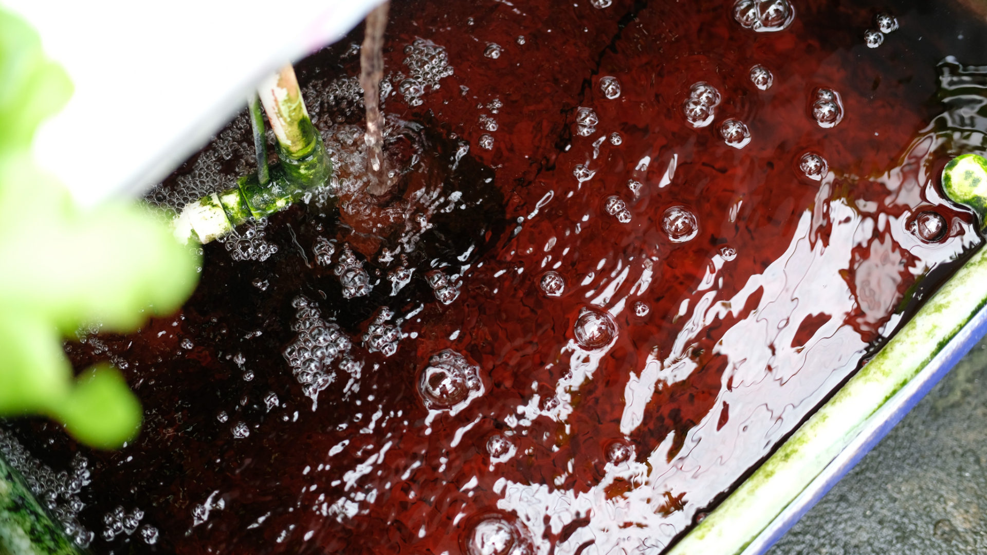 Água vermelha a fluir para reservatório azul com bordas verdes