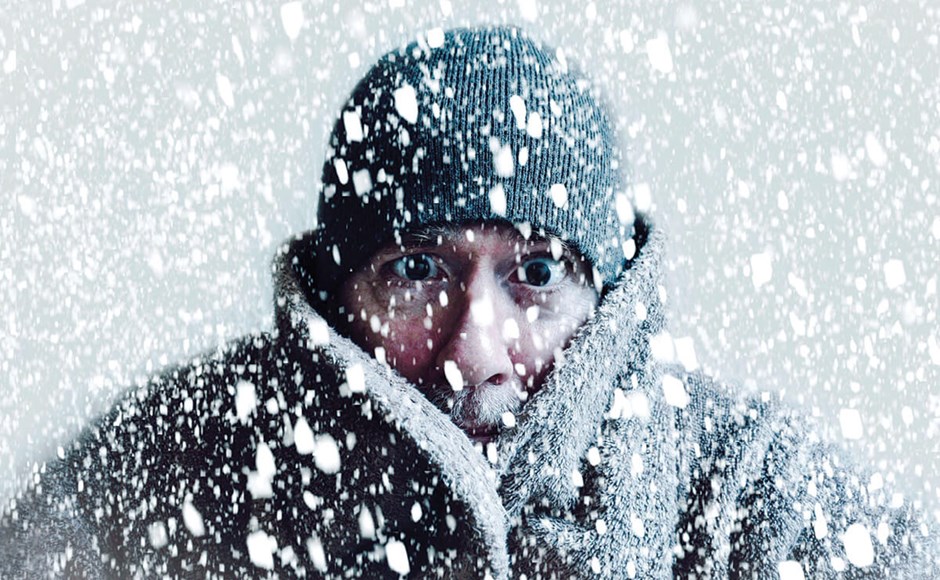 Homem com casaco grosso e gorro preto na neve