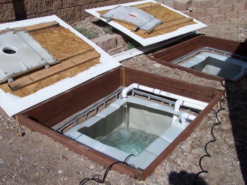 Três tanques enterrados para aquicultura com estrutura de madeira e tubos de água